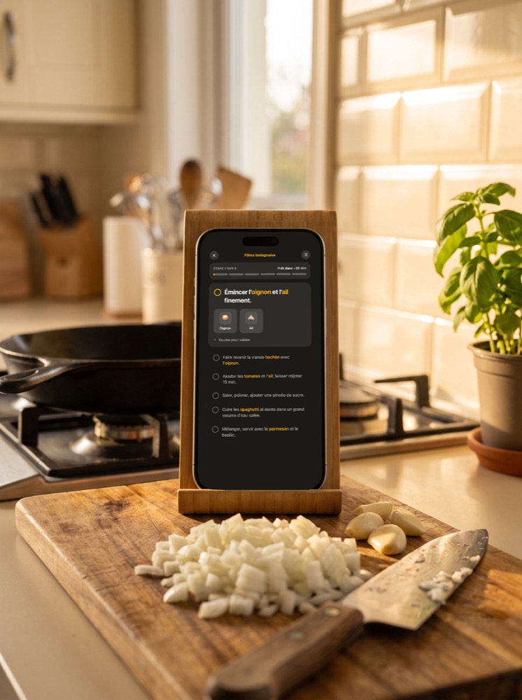 Le mode cuisine de Nyama sur un iPhone posé sur un support, au-dessus d'une planche à découper